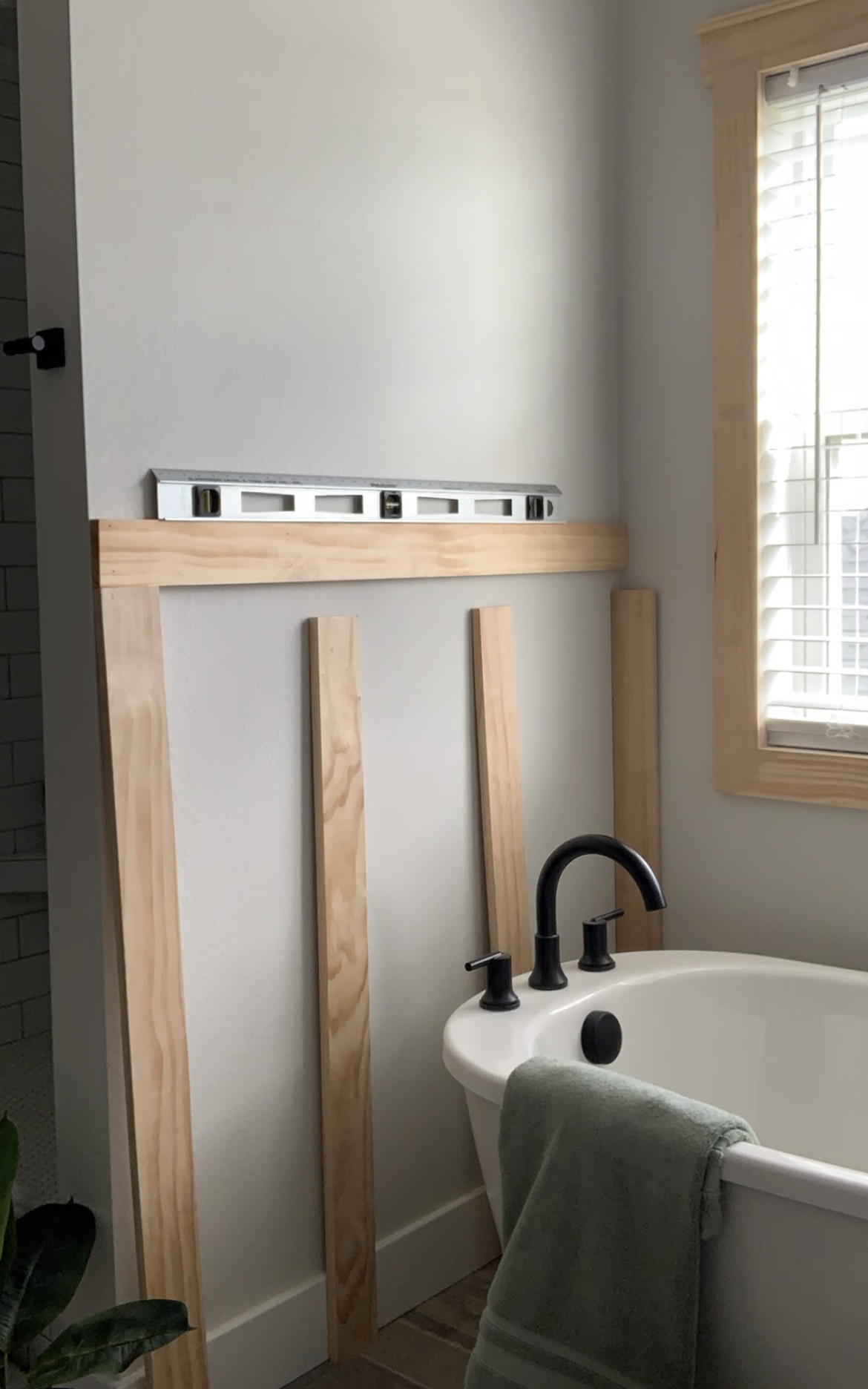 Wood boards for board and batten laid out on the bathroom wall.