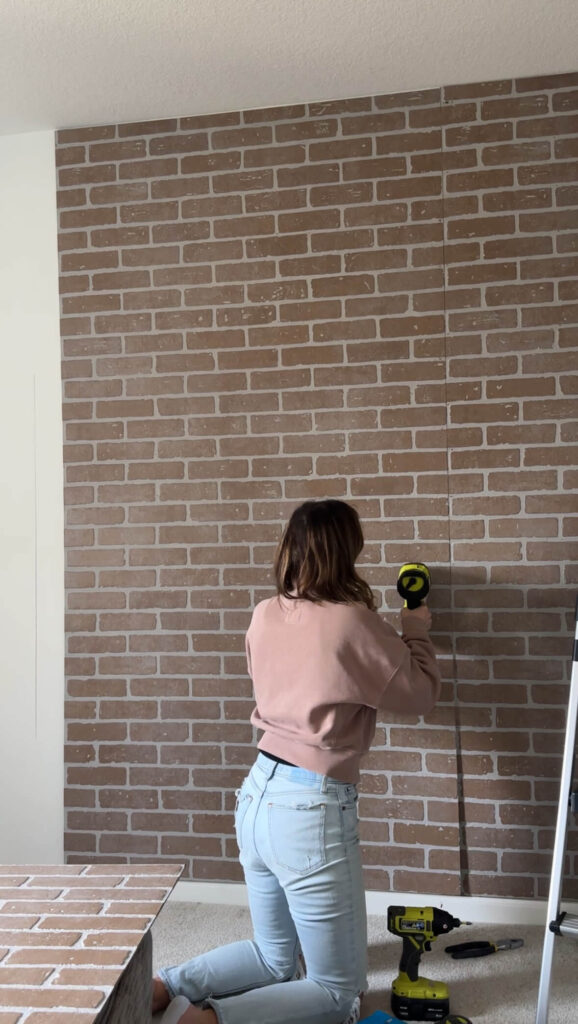 Melissa, from Lake and Lumber, using the Ryobi nail gun to adhere the faux brick panels to the wall 