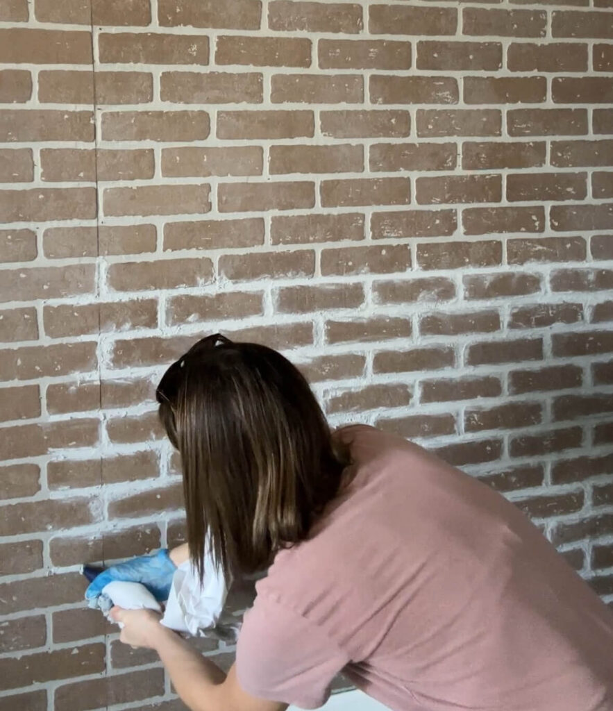Melissa Tyler applying the sanded grout to the faux brick wall 