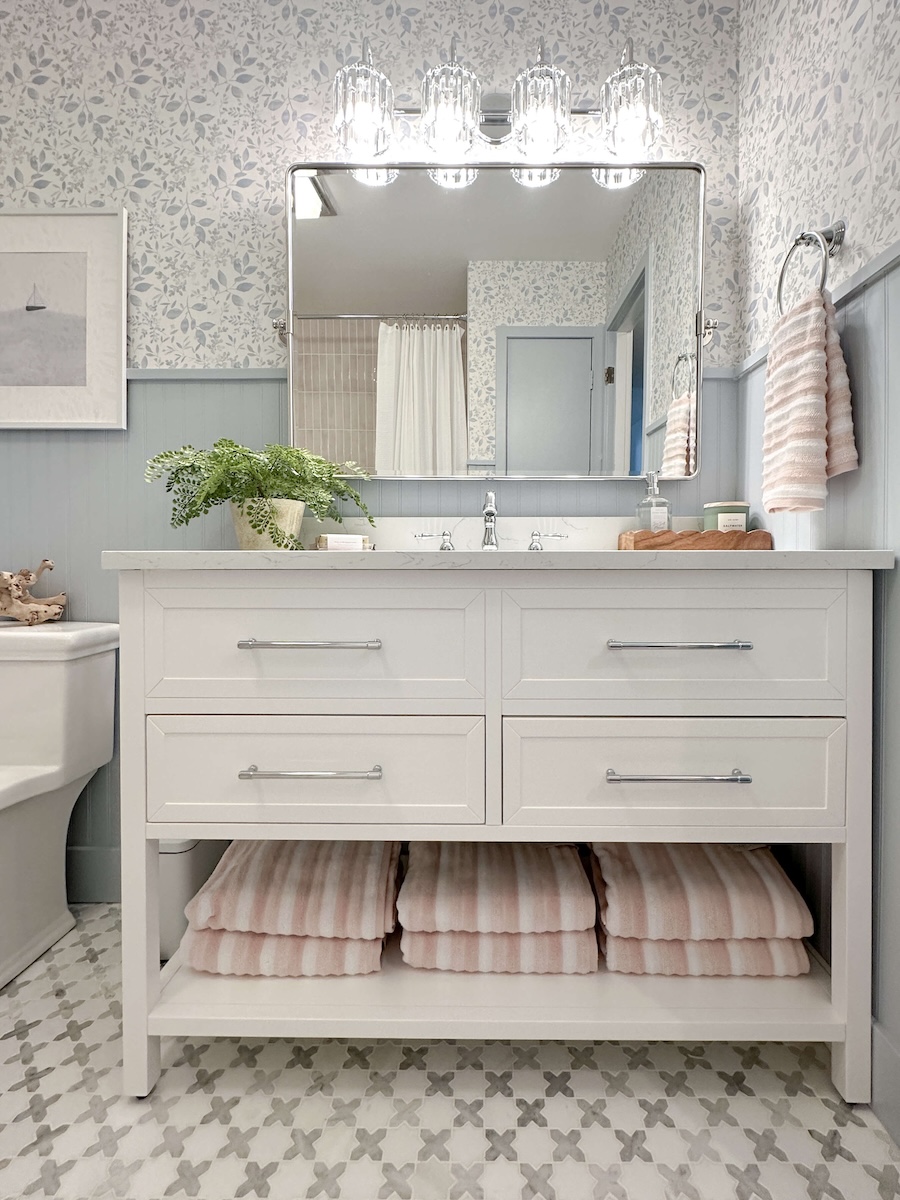 DIY Bathroom Renovation Reveal of the white vanity with mirror and light fixture hanging above it. 