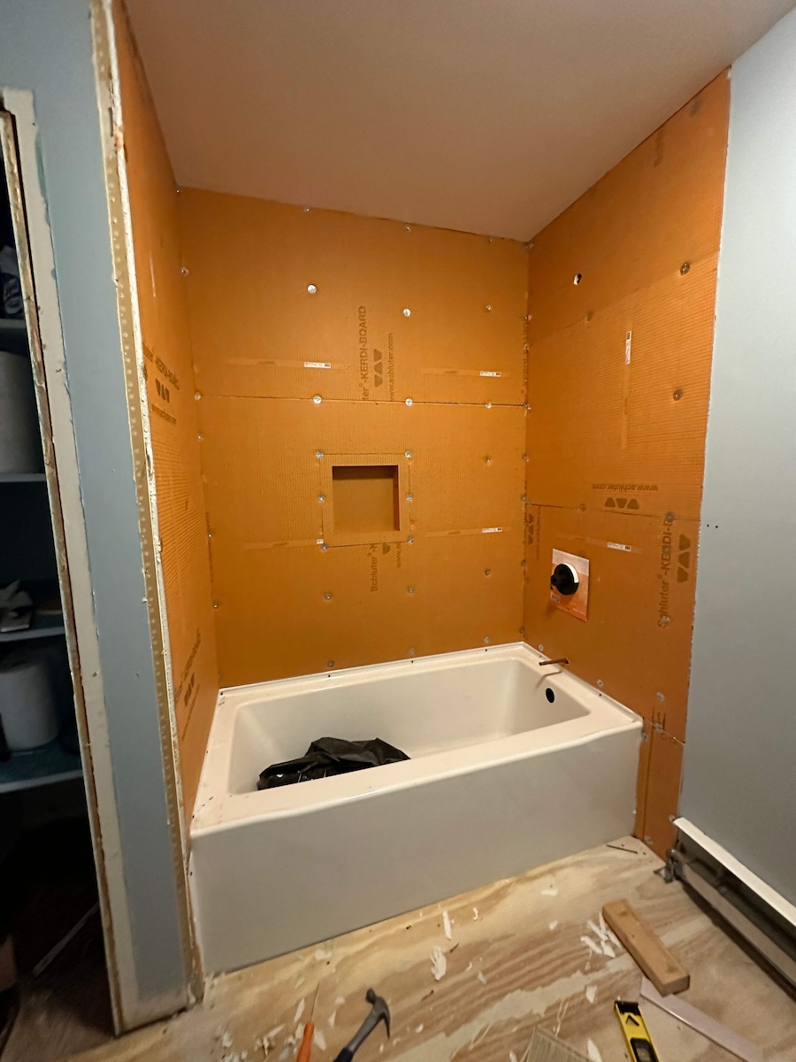 The Schluter board installed on all three wall os the shower with the white tub sitting in the middle. Now, it's ready for tiling! 