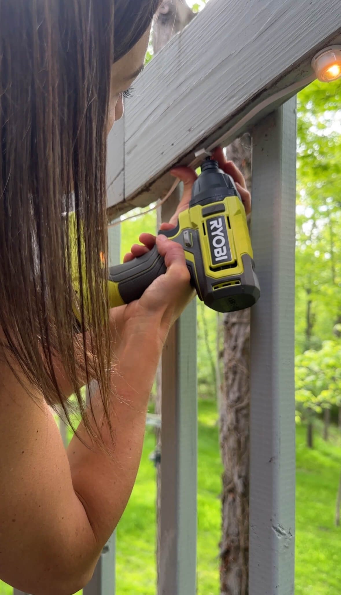 Melissa Tyler installling Enbrighten cafe lights to the railing of her porch.