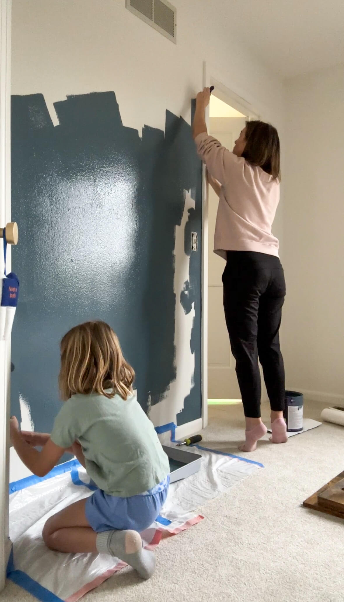 Two people painting a bedroom wall for a boy's bedroom makeover.