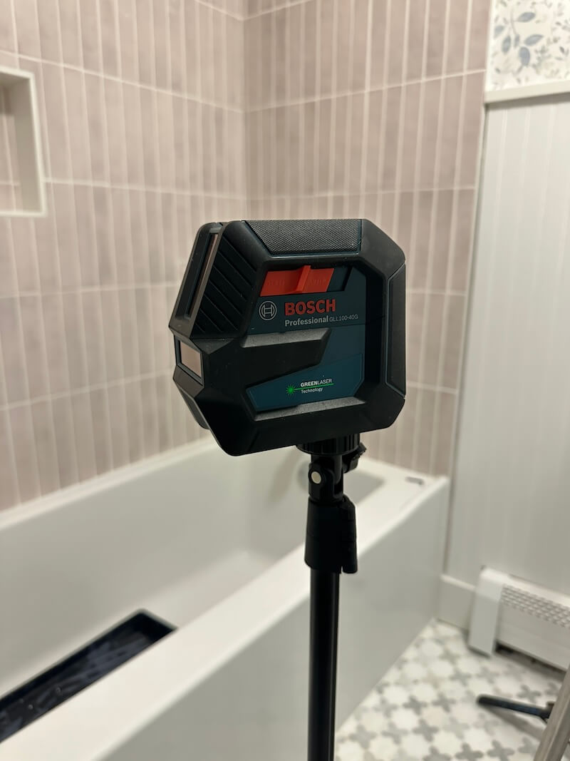 Bosch Laser Level that's sitting on a tripod to measure for the beadboard in the middle of the bathroom. 