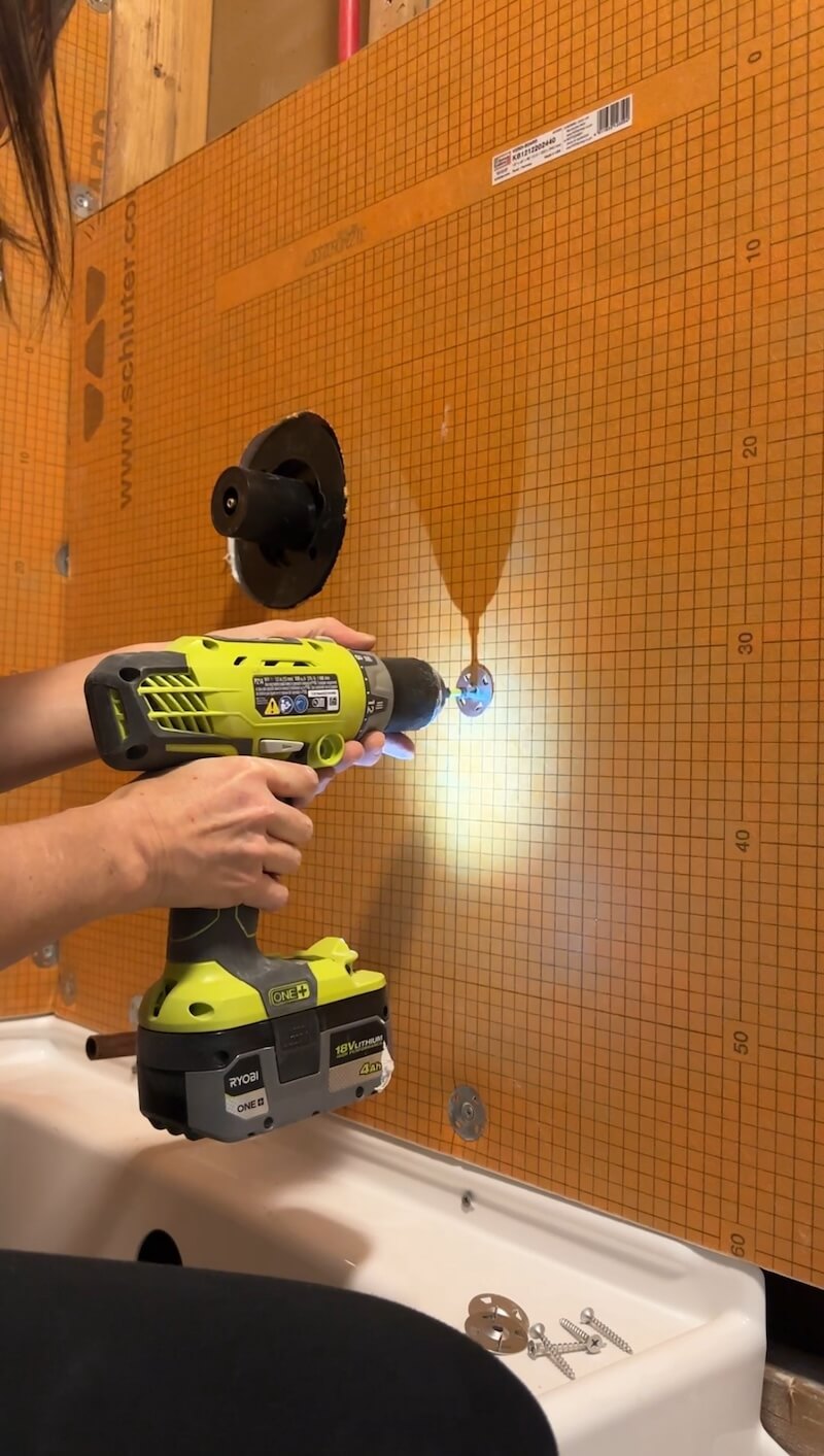 Melissa using a drill to install the special fasteners in the Kerdi board. 