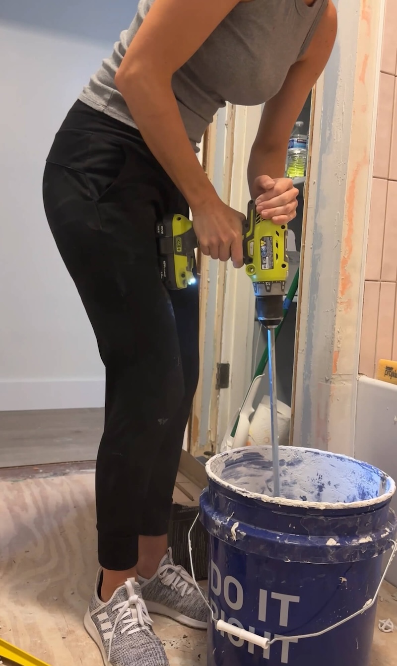 Melissa Tyler using a drill and paddle to mix a bucket of thinset before laying Schluter Ditra membrane. 