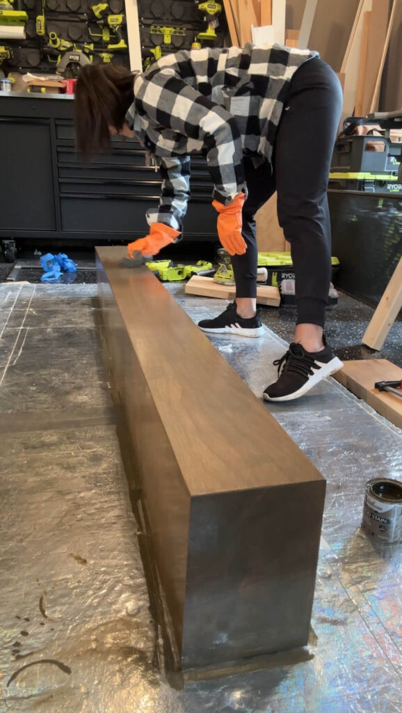 Melissa Tyler staining her DIY fireplace mantle. 