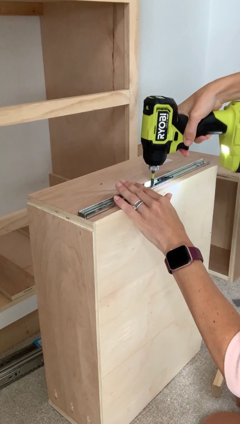 Melissa Tyler drilling the drawer slides on the back of drawers for her DIY custom closet. 