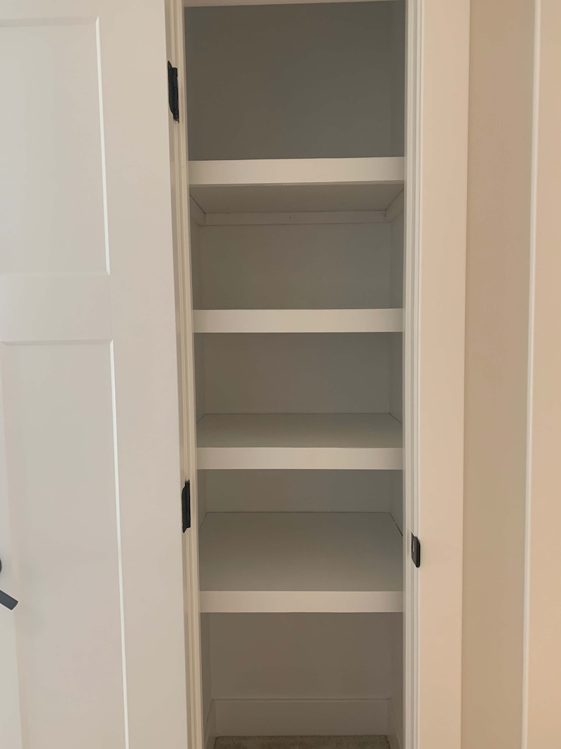 Open linen closet with 4 completed DIY closet shelves. 