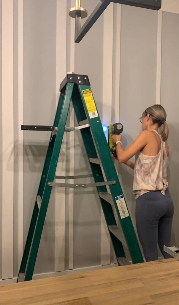 Melissa Tyler nailing MDF boards to the dining room wall.