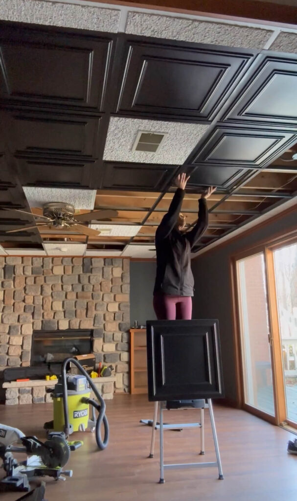 Melissa Tyler popping in tiles for her basement drop ceiling.