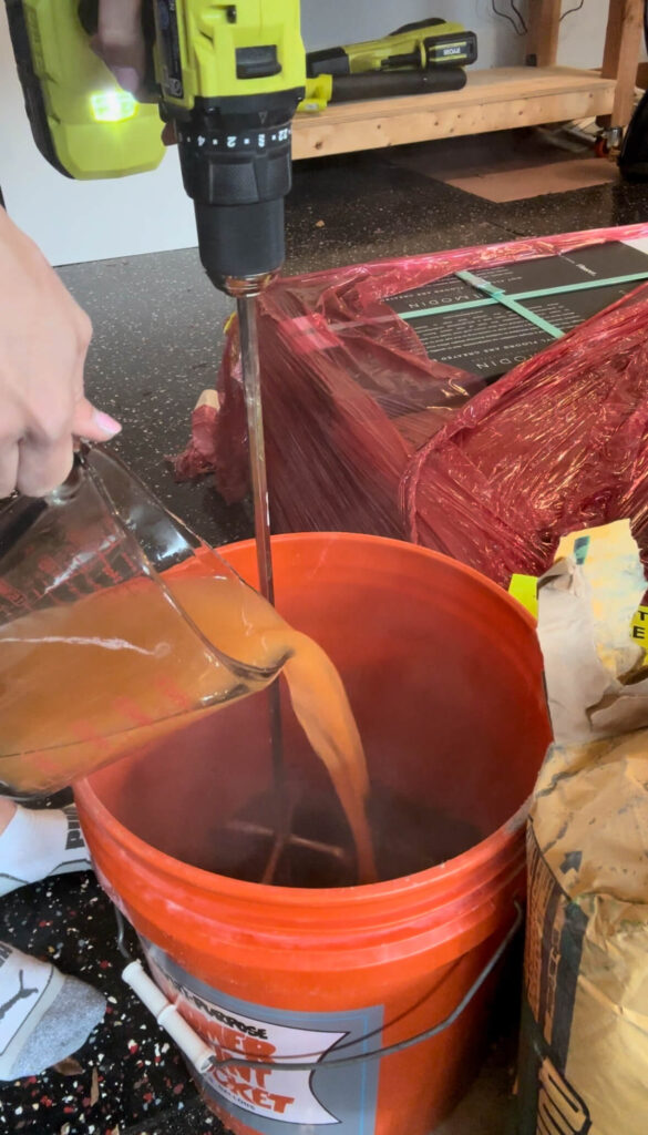 Melissa Tyler mixing mortar in an orange bucket. 