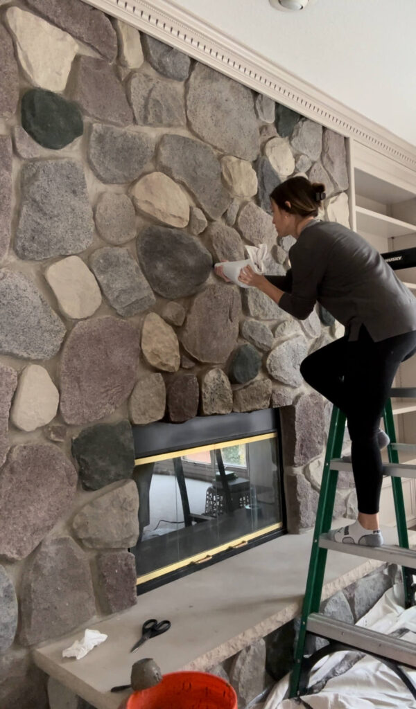 Melissa Tyler piping mortar in between her fireplace stones. 