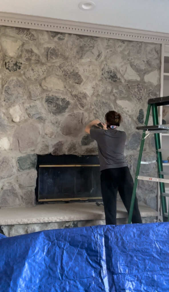 Melissa Tyler sanding the mortar and stone on her fireplace.